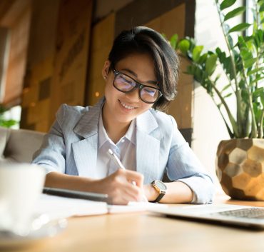 cheerful-asian-lady-filling-papers-in-cafe-R2FXU9G.jpg